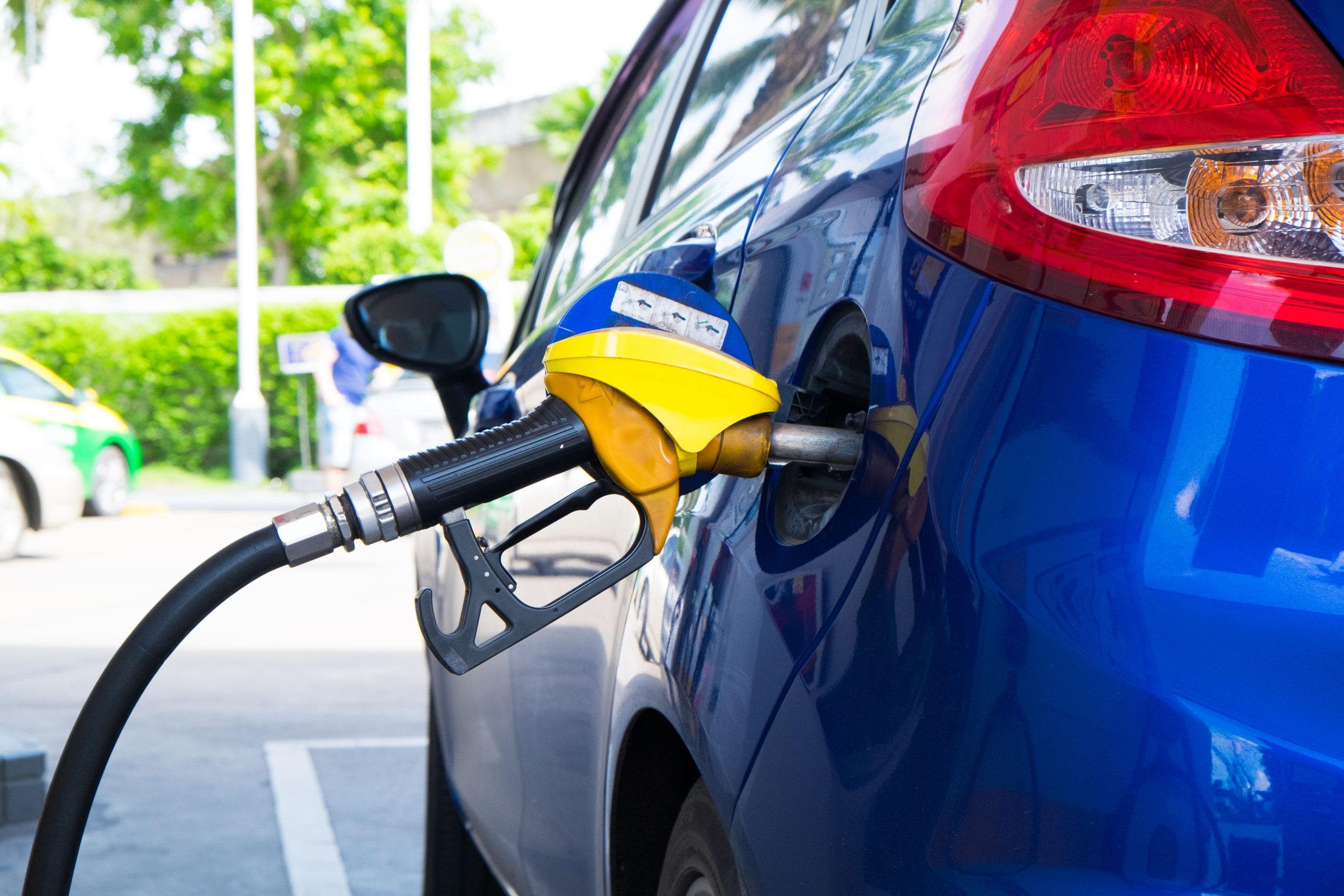 Used car refueling at a gas station with a yellow pump