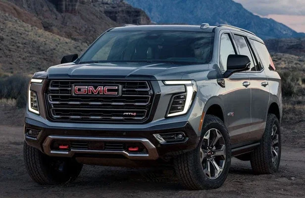 A gray GMC Yukon AT4 parked on a dirt trail below desert mountains