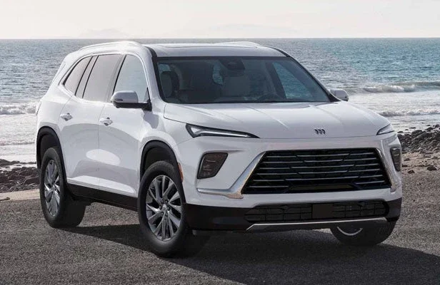A white Buick Enclave parked on a beach with the ocean behind it