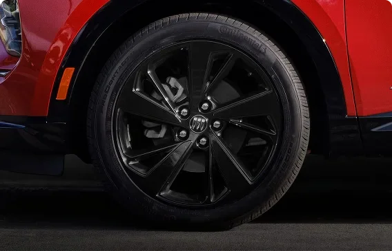 Close-up of a Carbon Flash Metallic painted alloy wheel on a red Buick Envision Sport Touring