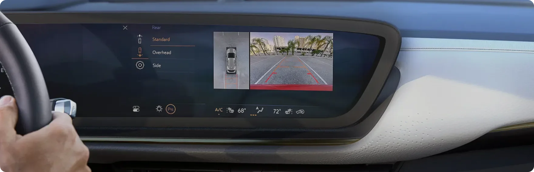 Driver's hands on the Envision Avenir steering wheel with the rear camera view on the ultrawide display