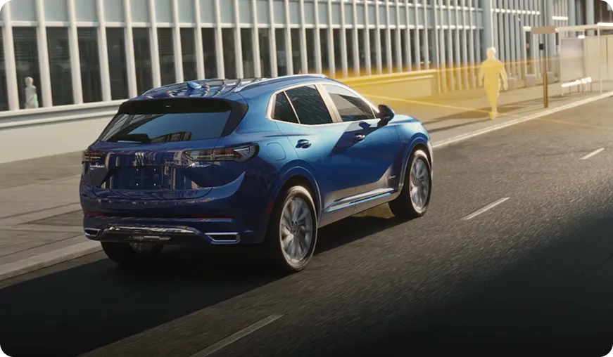 Blue Buick Envision driving a city street alongside a glass office building