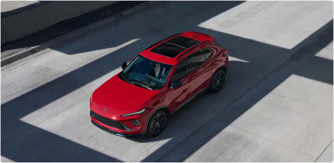 Overhead view of a red Buick Envision driving between lane markings on a concrete roadway