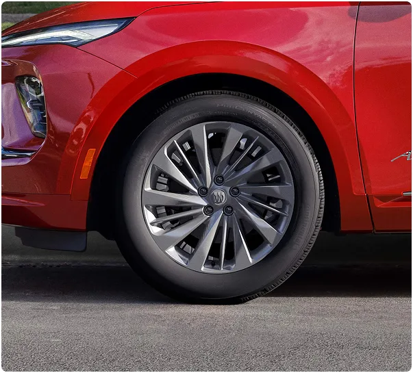 Front wheel and Avenir badge on a red Buick Envision parked on a street