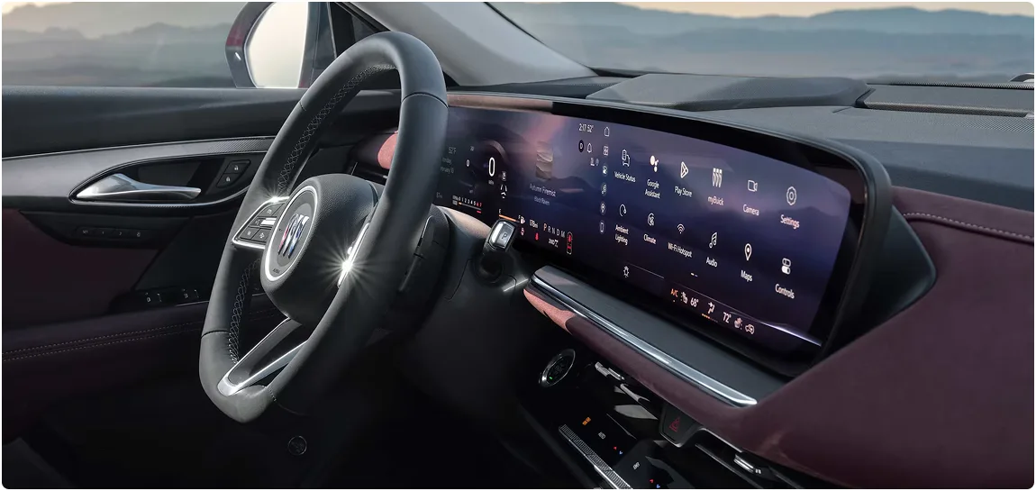 Buick Envision steering wheel and ultrawide display with a mountain view through the windshield