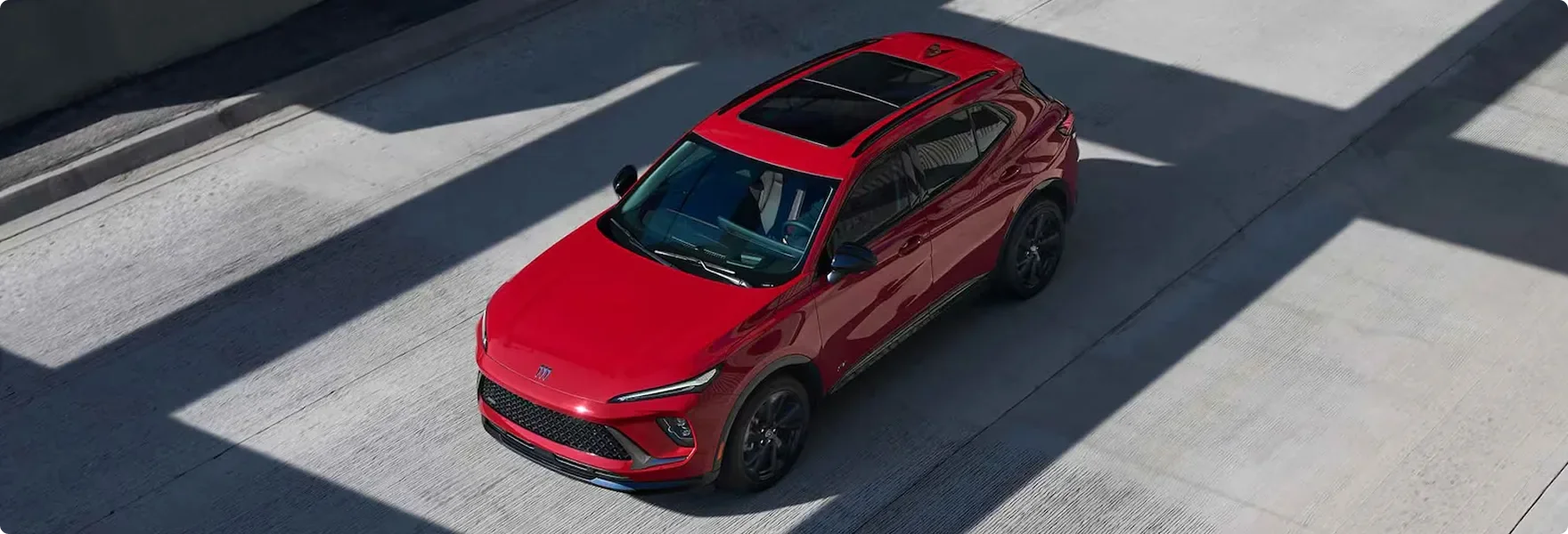 Overhead view of a red Buick Envision driving between lane markings on a concrete roadway