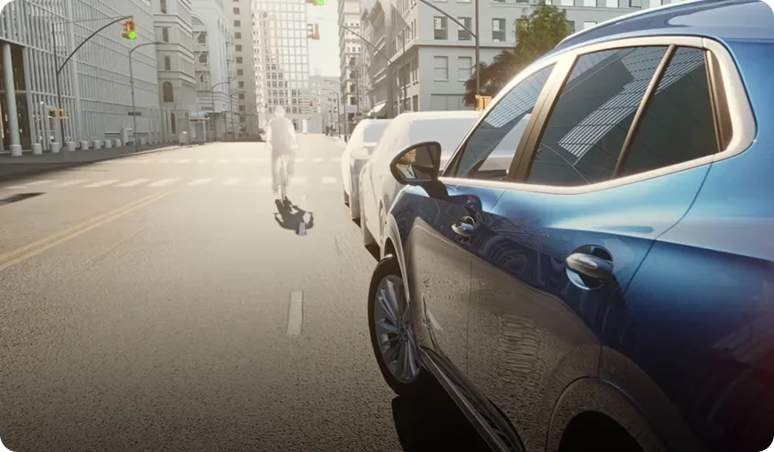 Blue Buick Envision passing a cyclist on a city street beside parked cars