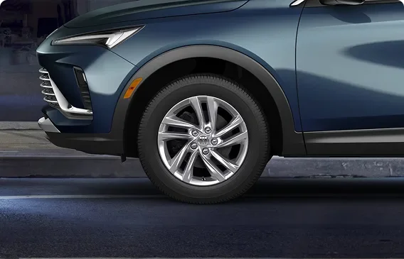 Front wheel and fender of a dark blue Buick Envista with a bright silver-painted aluminum wheel