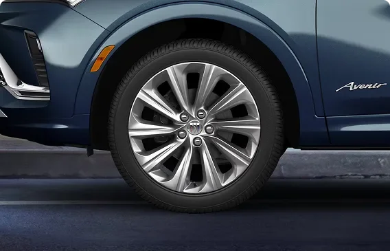 Close-up of a Pearl Nickel finish aluminum wheel on a dark blue Buick Envista Avenir