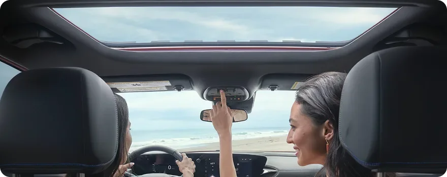 Two people in the front seats of a Buick Envista looking up through the open moonroof