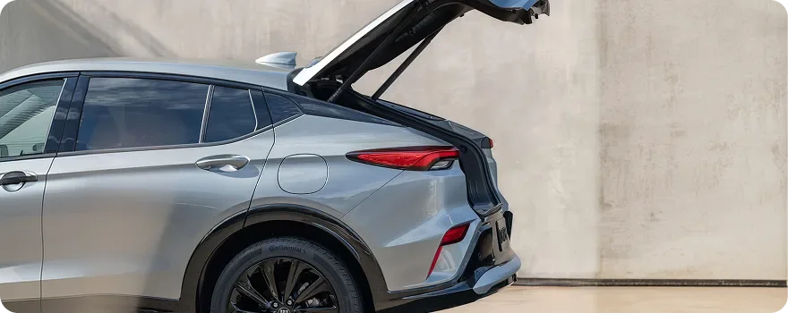 Silver Buick Envista in profile with its power liftgate raised against a concrete wall