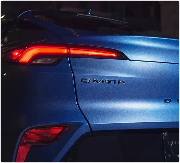 Rear quarter of a blue Buick Envista at night showing the Envista badge and tail lamp