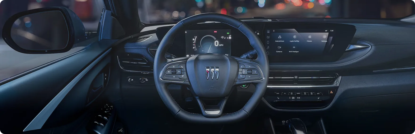 View across the Buick Envista cockpit at night with the driver display and touchscreen lit