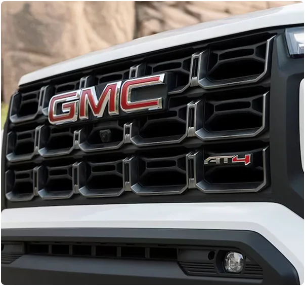 Close-up of a white GMC Canyon AT4's grille and LED headlamp