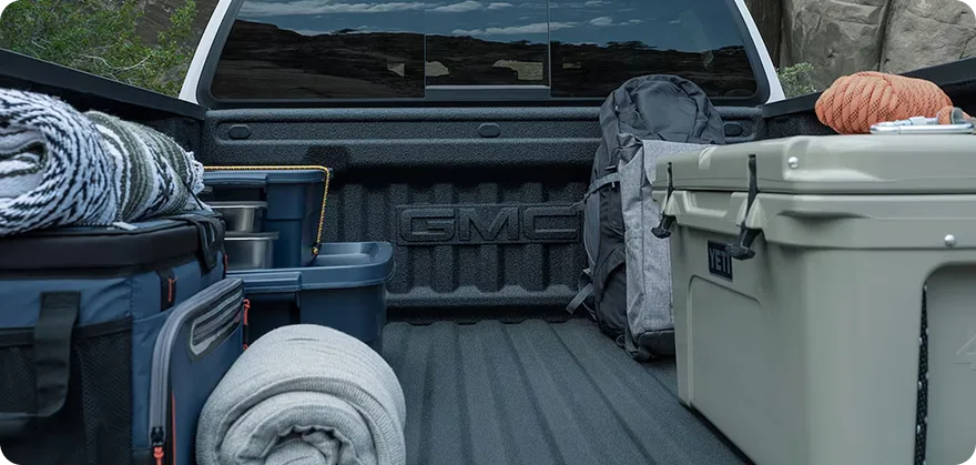 The Canyon's cargo bed loaded with duffel bags, a cooler and rolled camping gear