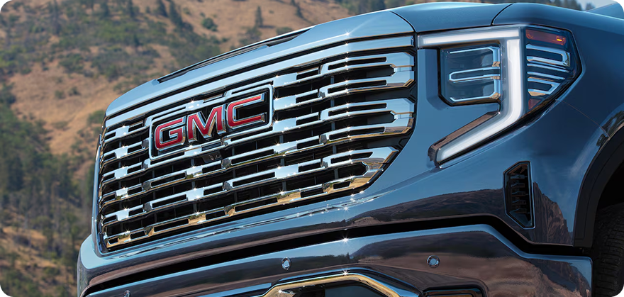 Close-up of the chrome Denali grille with red GMC lettering on a blue Sierra 1500