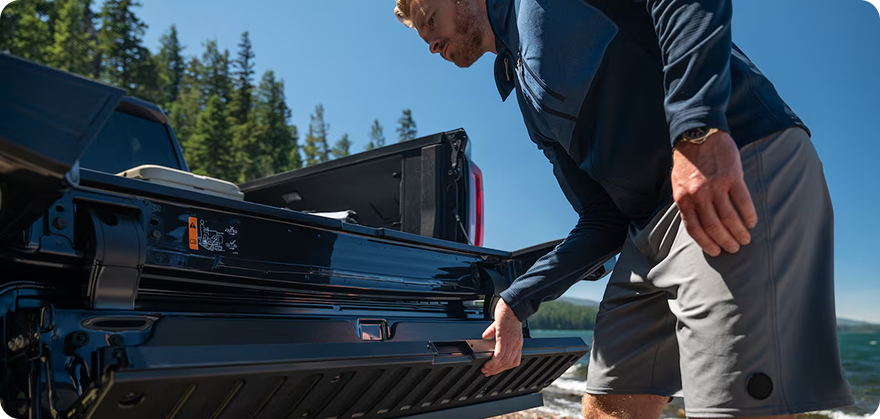 Man lowering the inner gate of the MultiPro Tailgate on a GMC Sierra 1500 beside a lake