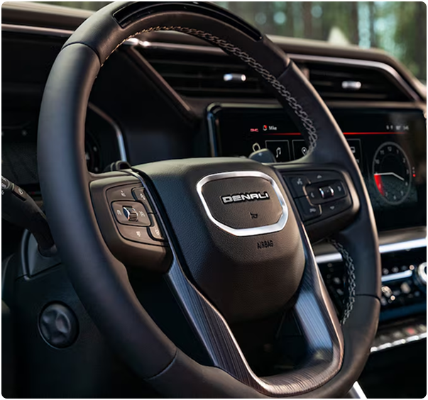 Close-up of the leather-wrapped steering wheel with Denali badging in a GMC Sierra 1500