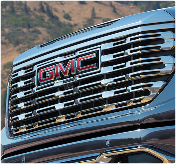 Close-up of the chrome Denali grille with red GMC lettering on a blue Sierra 1500