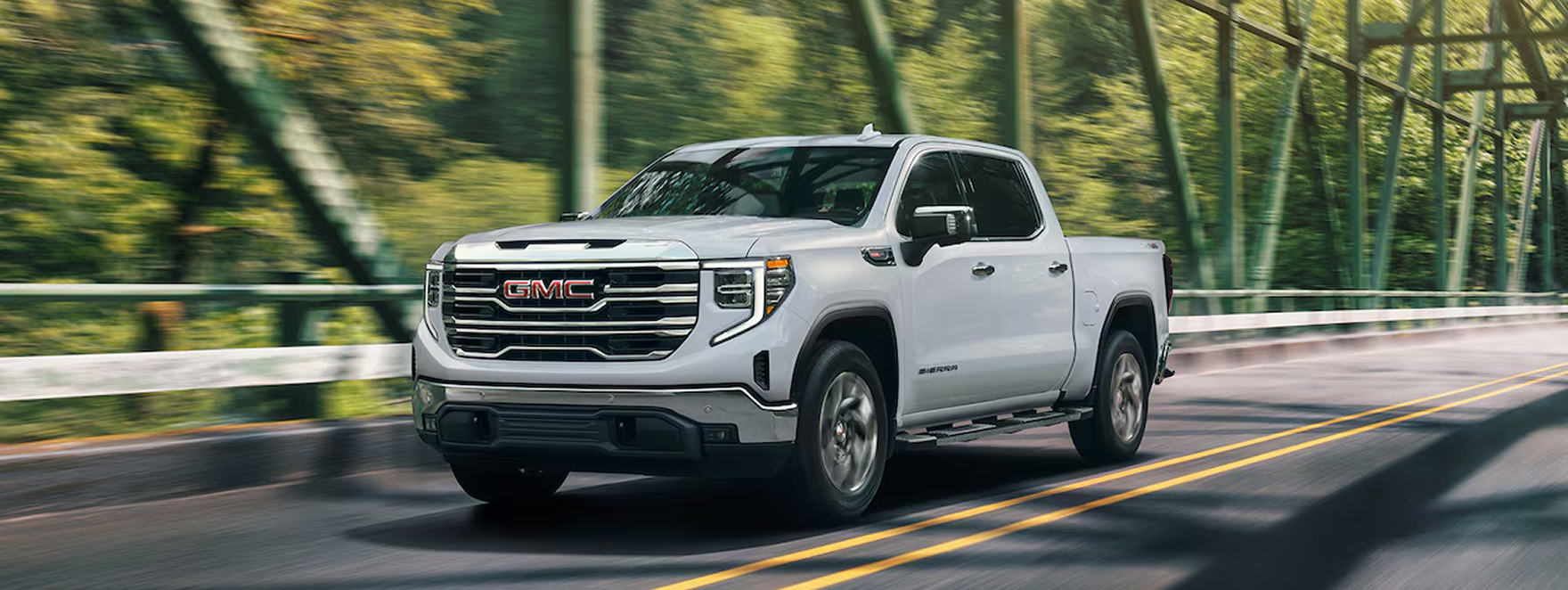 White GMC Sierra 1500 crossing a green steel truss bridge