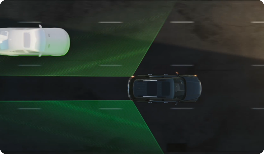 Overhead illustration of a GMC vehicle with green side blind zone areas and a car approaching in the next lane