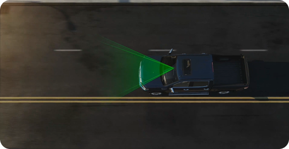 Overhead illustration of a blue GMC truck with a green sensor area ahead, driving beside a yellow center line