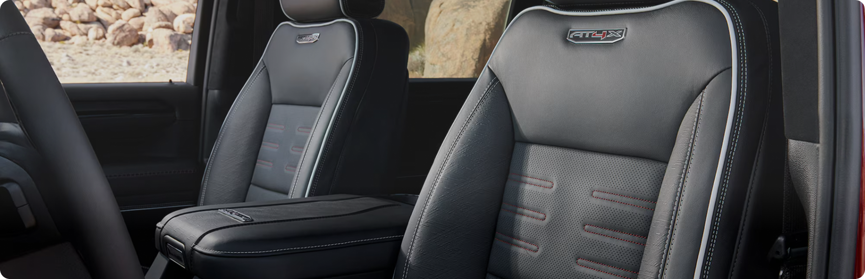 Black leather front seats in the GMC Sierra HD AT4X with AT4X badges on the headrests