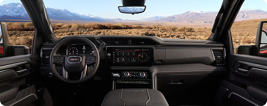 GMC Sierra HD front cabin seen from the rear seat, looking out through the windshield at a desert valley and mountains