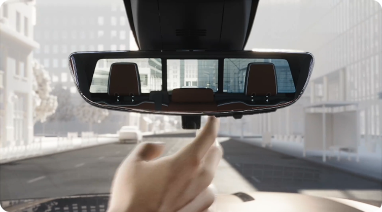 Hand adjusting the Rear Camera Mirror, which shows a wide camera view of the road behind