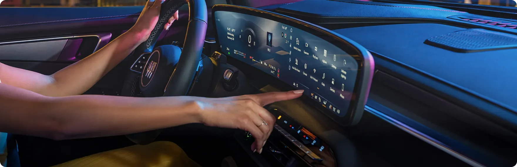 Driver reaching across the ultrawide display of the Enclave Sport Touring with violet ambient lighting