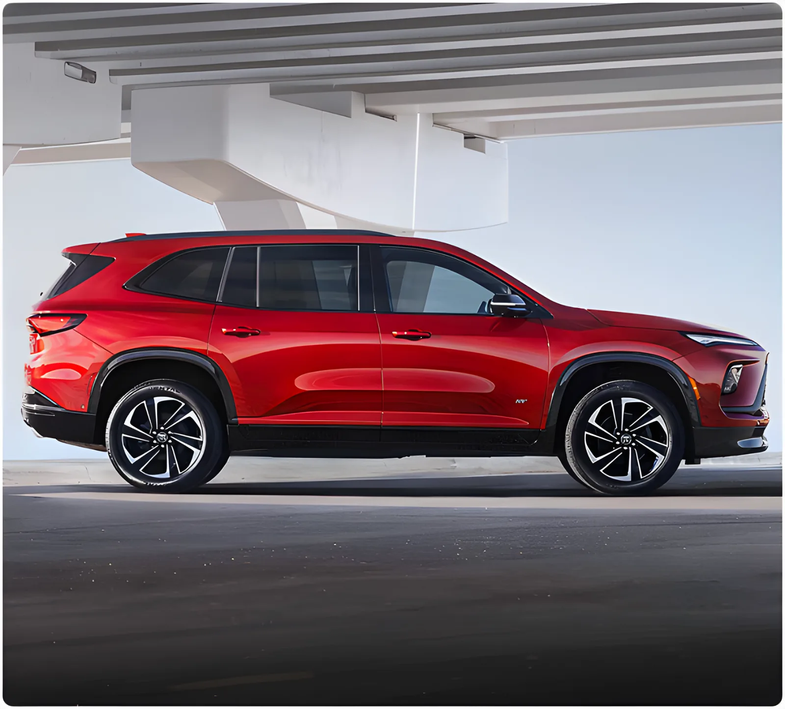 Red Buick Enclave parked under a concrete structure, seen in profile