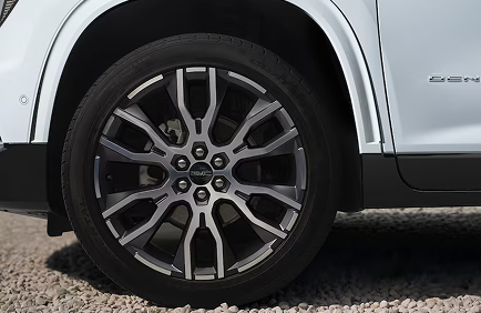 Wheel arch of a white GMC Acadia Denali Ultimate with a multi-spoke machined aluminum wheel