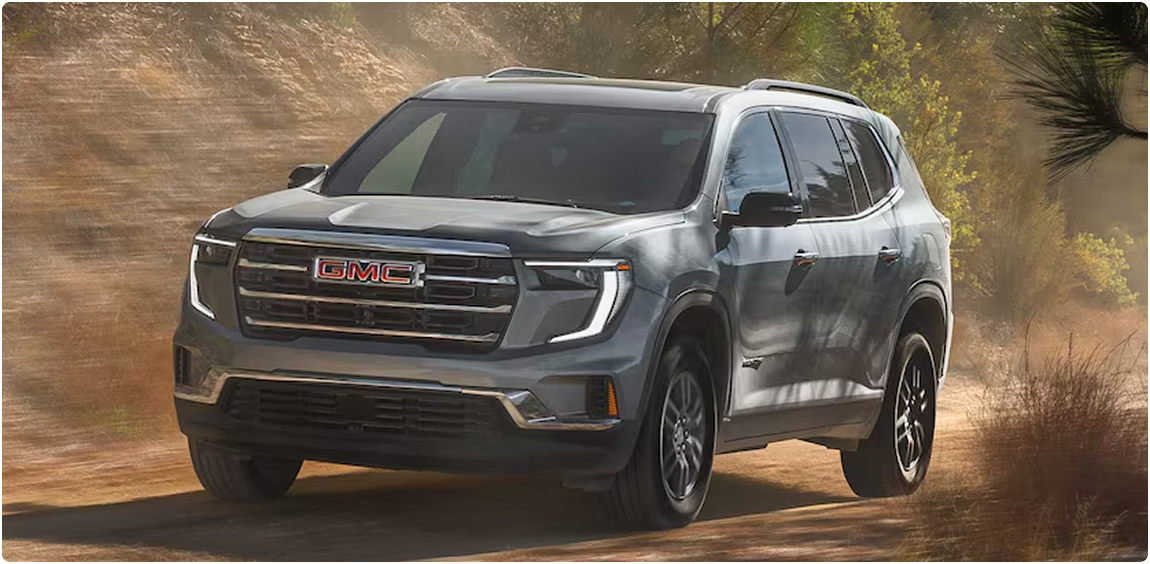 Gray GMC Acadia driving a dusty forest road, seen from the front