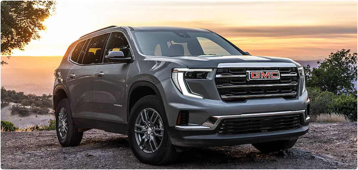 Gray GMC Acadia parked on an overlook at sunset, seen from the front three-quarter angle