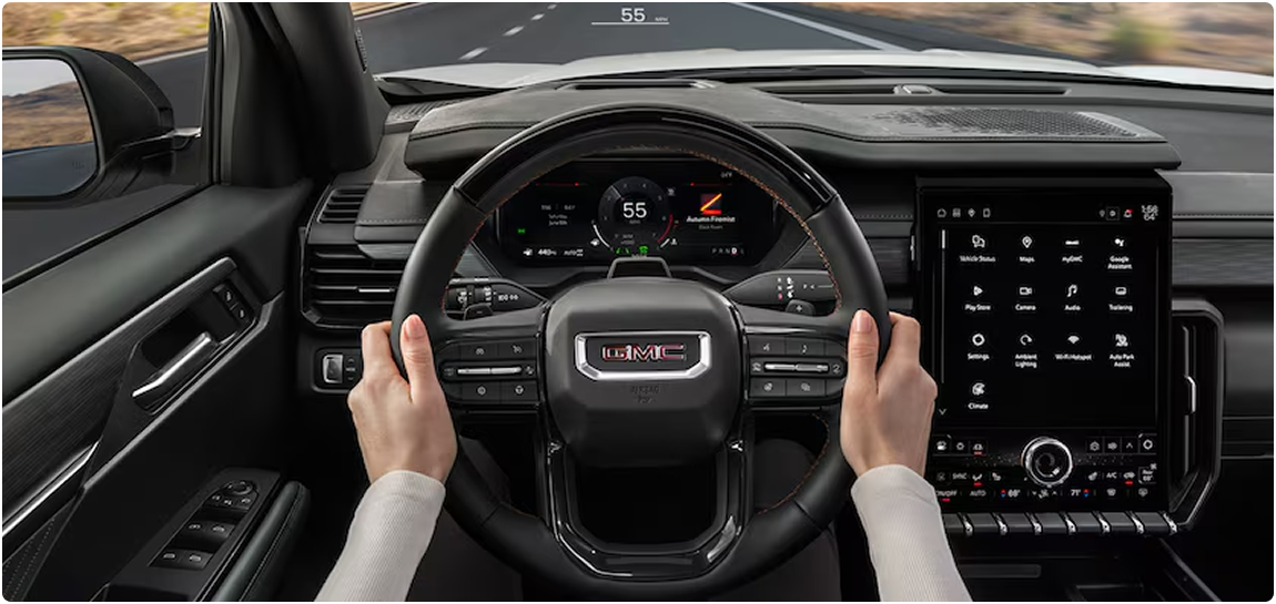 Driver’s hands on the GMC Acadia steering wheel with the digital cluster and center touchscreen ahead