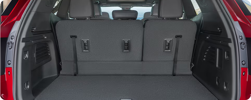 Open cargo area of a red GMC Acadia with the third-row seats upright