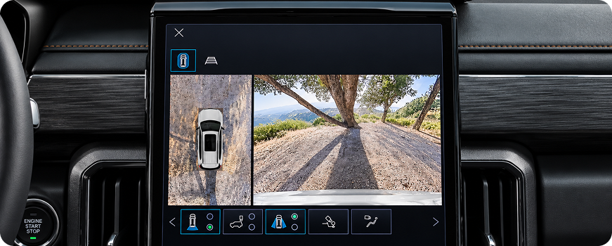 GMC Acadia center touchscreen showing a surround-view overhead camera beside a forward camera view