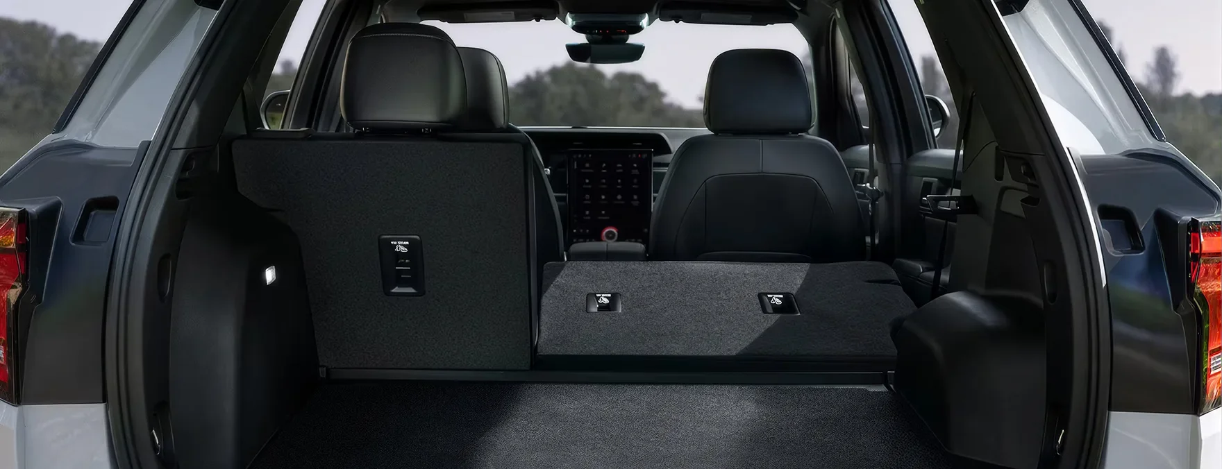 Open rear liftgate of a white 2027 GMC Terrain with the 60/40 split-folding rear seats folded down