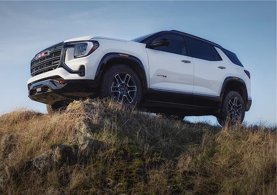 White 2027 GMC Terrain AT4 perched on a rocky outcrop, seen from the front three-quarter angle