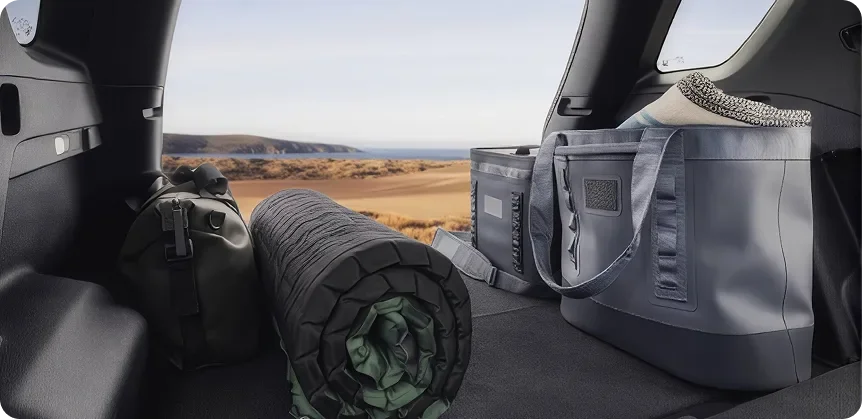 The 2027 GMC Terrain's rear cargo area loaded with a cooler bag and rolled camping gear