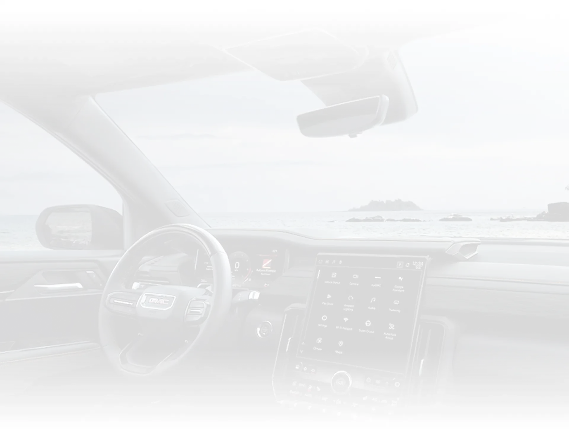 Faint backdrop of the view across the 2027 GMC Terrain's dashboard and side mirror toward the water