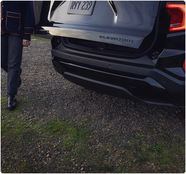 A person walking toward the open liftgate at the rear of a 2027 GMC Terrain Elevation