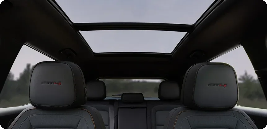 Looking up through the 2027 GMC Terrain's panoramic sunroof from behind the AT4 front-seat headrests