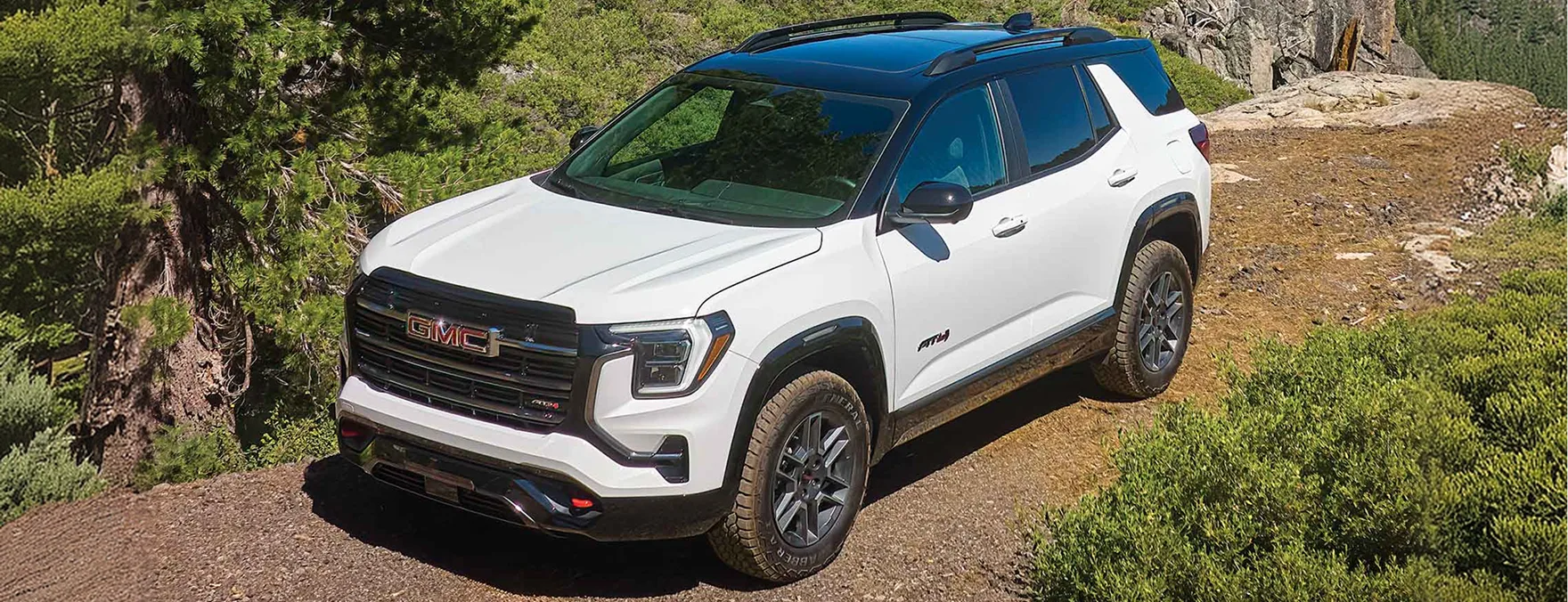 White 2027 GMC Terrain AT4 with a black two-tone roof parked on a rocky mountain trail