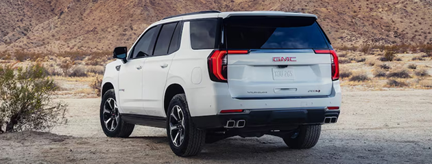 White GMC Yukon AT4 parked in the desert, seen from the rear three-quarter angle
