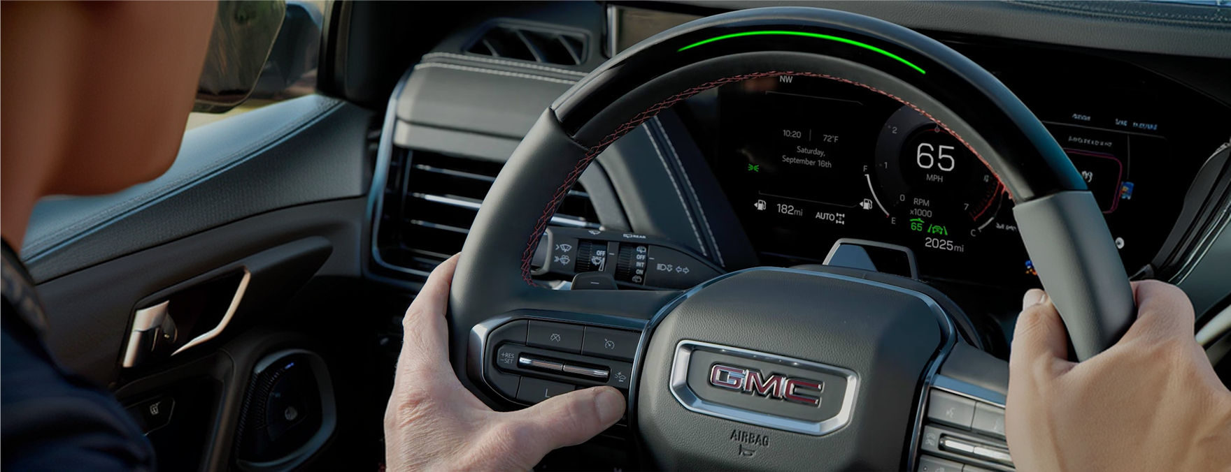 Driver using Super Cruise in a GMC Yukon, the steering wheel light bar glowing green