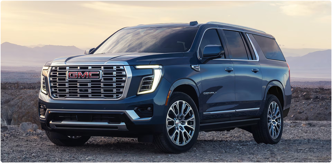 Blue GMC Yukon Denali parked on a desert overlook at sunset, seen from the front three-quarter angle
