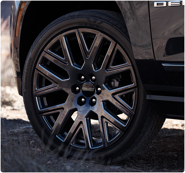 Close-up of a dark multi-spoke GMC Yukon Denali wheel with a GMC center cap
