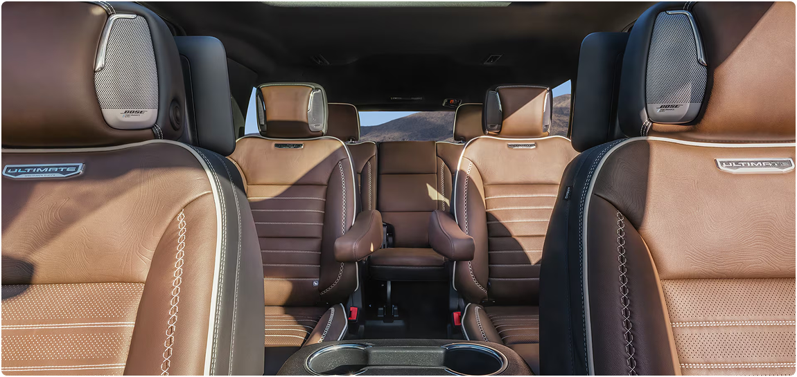 Brown leather Yukon Denali Ultimate seats with Bose headrest speakers, seen from the front row looking back