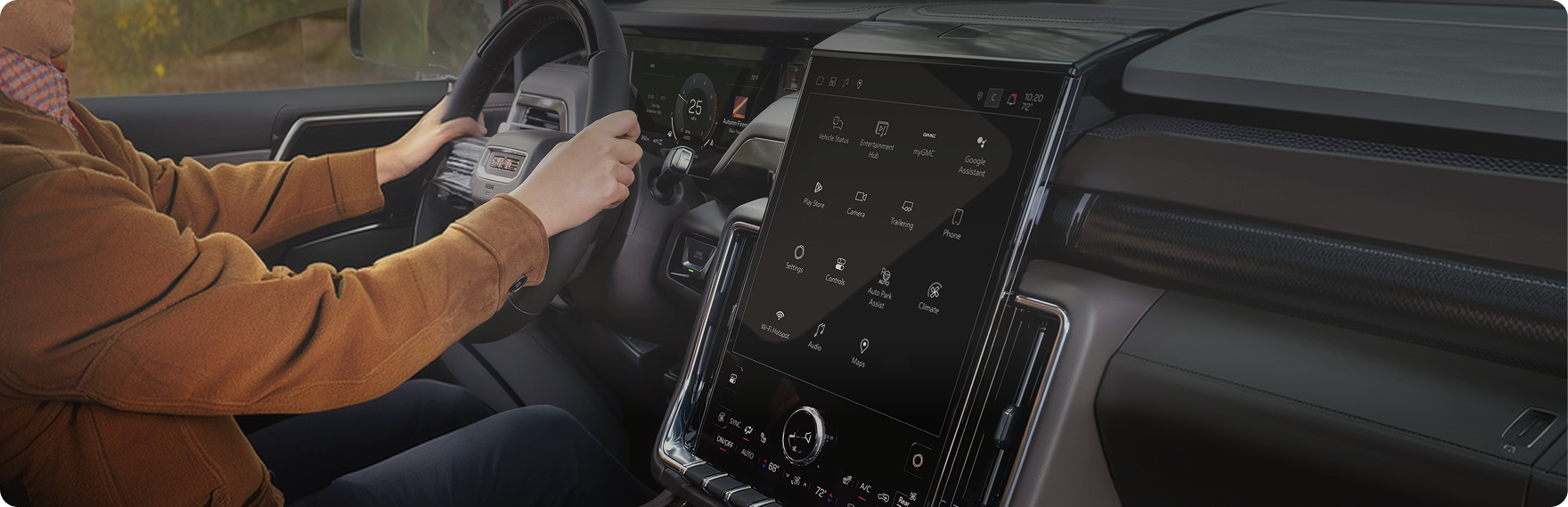 Driver in a tan jacket at the wheel of a GMC Yukon beside the large portrait center touchscreen